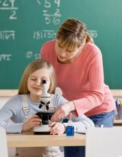 niña mirando por el microscopio con profesora